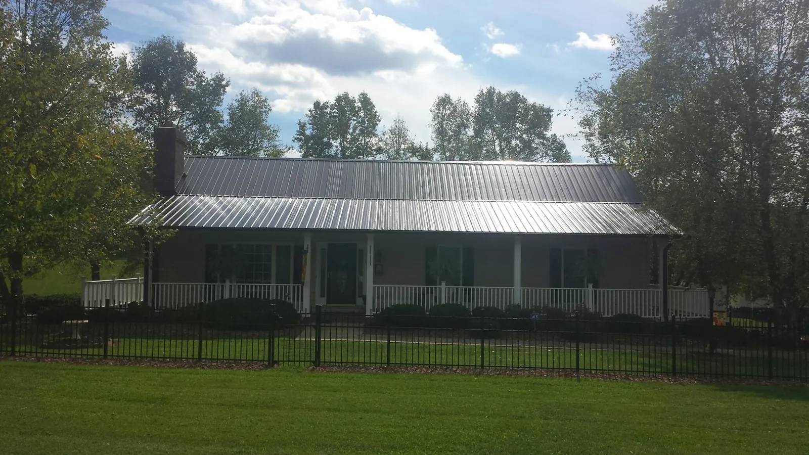 Gray metal roof on a brick ranch with a full width front porch — Gutter Guard Installation work by our crew in Crawford