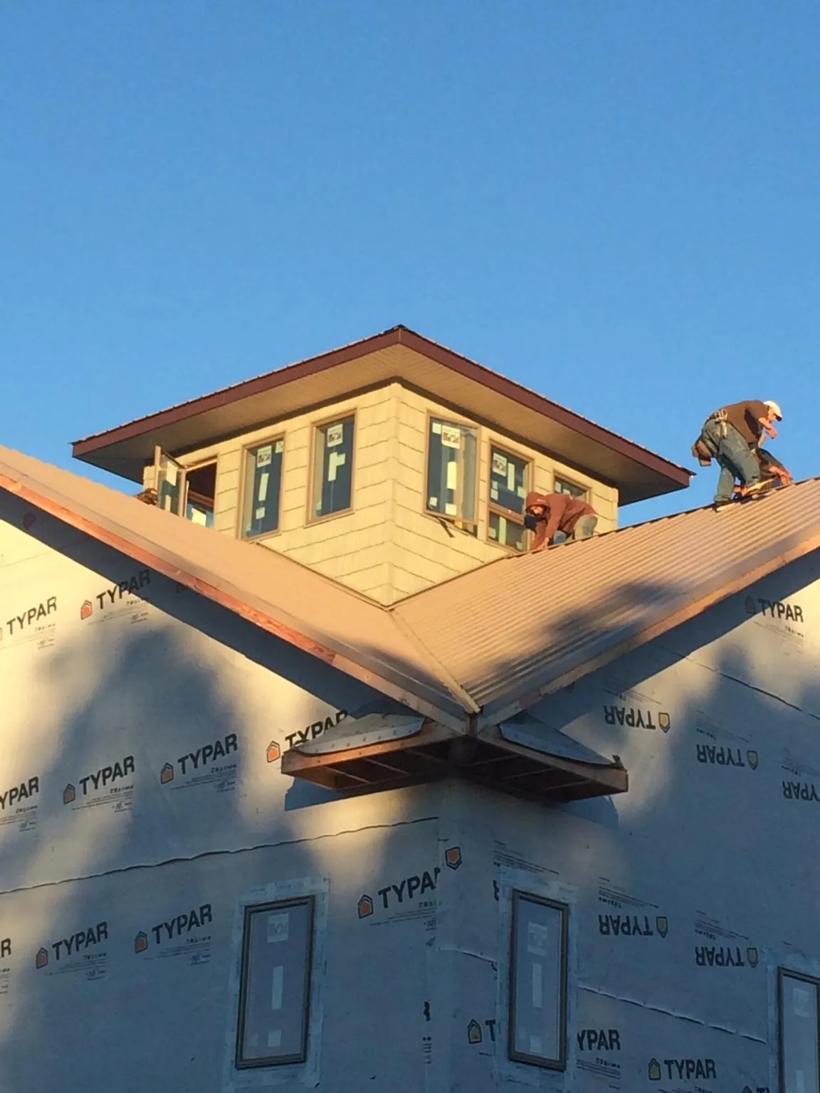 Roofers working around a rooftop cupola on a new metal roof at sunset — Roof Waterproofing in Crawford by Roofing Brothers